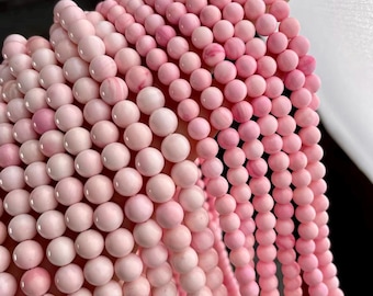 May include: A strand of pink and white gemstone beads. The beads are round and smooth, and they have a natural, organic look.