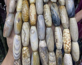 May include: A strand of polished, oval-shaped beads in shades of cream, tan, and gray. The beads have unique patterns and textures, resembling natural stone. The beads are strung together, ready for jewelry making or crafting.