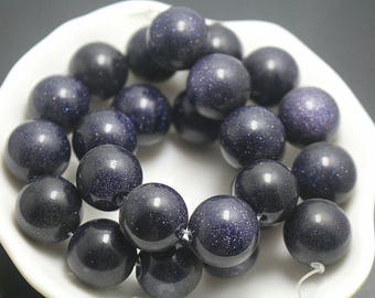 May include: A collection of round, dark blue beads with a shimmering, glitter-like texture throughout. The beads are smooth, polished, and spherical, featuring deep navy tones with tiny, reflective specks that catch the light, arranged in a cluster.