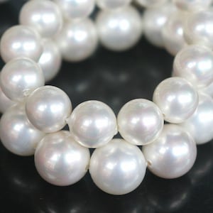 Peut inclure: Un collier de perles blanches, disposées en cercle, chaque perle reflétant la lumière.