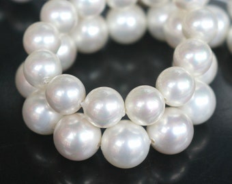 May include: A strand of white pearls, arranged in a circular pattern, with each pearl reflecting light.