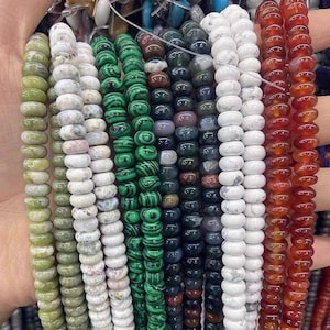 May include: A variety of gemstone beads in different colors and patterns, including green, white, brown, and red. The beads are strung together on a string and are ready to be used for jewelry making.