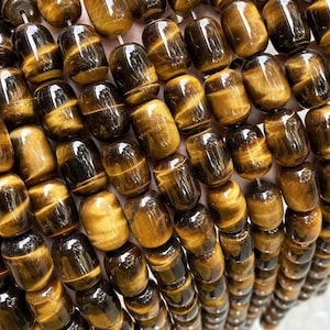 May include: A close-up of a strand of tiger's eye beads. The beads are a rich golden brown color with a subtle shimmer. They are all smooth and polished, and they are arranged in a neat row.