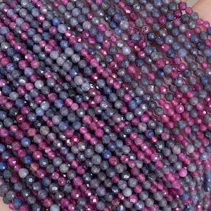 Op de afbeelding: Een streng facetgeslepen edelsteen kralen in tinten blauw en roze. De kralen zijn klein en rond en zijn aan elkaar geregen op een doorzichtige draad.