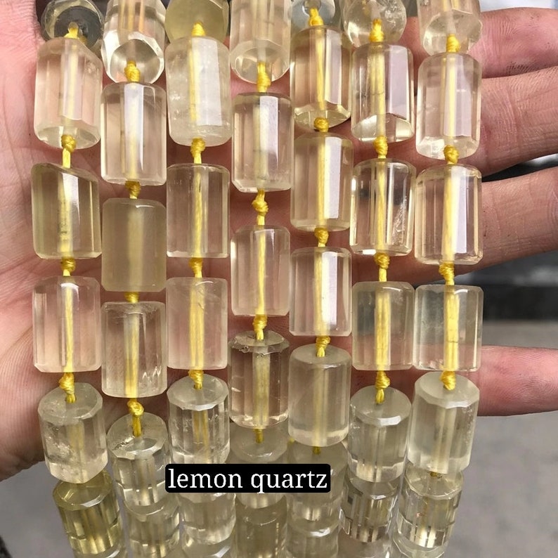 May include: A strand of lemon quartz beads, each bead is faceted and has a rectangular shape. The beads are strung on a yellow thread.