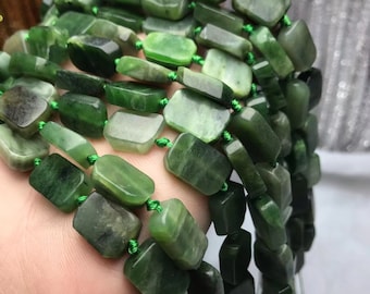 Pode incluir: Um fio de contas de jade verde escuro, cada conta é retangular e polida. As contas são enfiadas em um cordão verde.