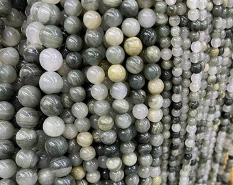 May include: A strand of round, gray and white gemstone beads. The beads have a striated pattern and are strung on a clear thread.