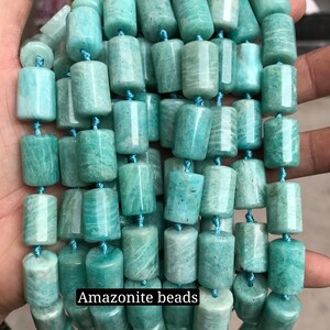 May include: A strand of smooth, light green amazonite beads. The beads are cylindrical and have a slightly mottled appearance.  Amazonite beads.