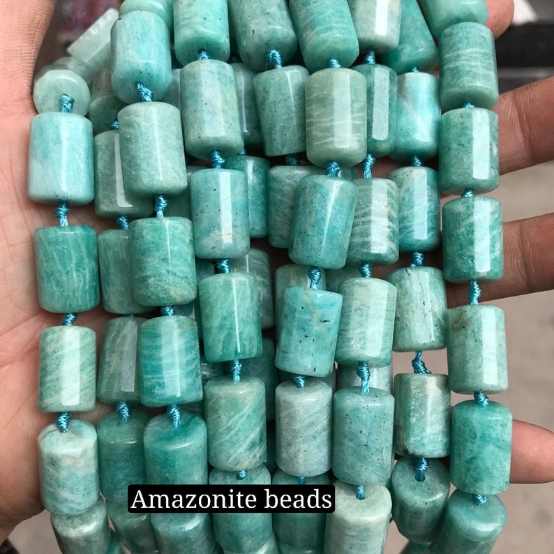 May include: A strand of smooth, light green amazonite beads. The beads are cylindrical and have a slightly mottled appearance.  Amazonite beads.