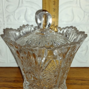 Peut inclure: Un sucrier en verre transparent avec un couvercle et un motif de verre taillé complexe. Le bol mesure environ 13 cm de haut.
