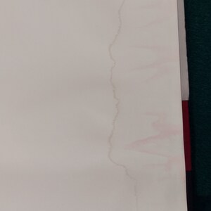 May include: A close-up of a white surface with a pink water stain running down the side.