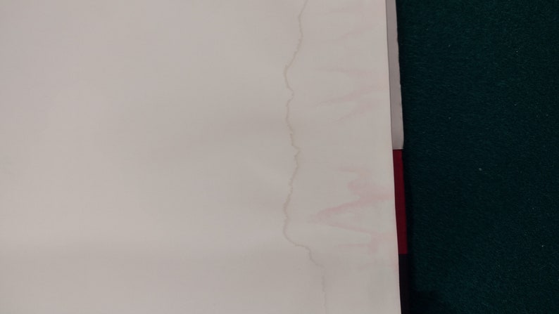 May include: A close-up of a white surface with a pink water stain running down the side.
