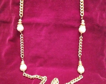 Puede incluir: Un collar de cadena dorada con cuatro acentos de perlas blancas. La cadena es de estilo grueso y robusto.