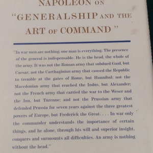 May include: A vintage book cover with a white background and brown text. The title is "Napoleon on "Generalship and the Art of Command". The text on the back cover is a quote from Napoleon about the importance of leadership in war.