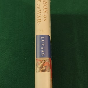 May include: A white book with gold lettering on the spine. The title is "Napoleon on the Art of War" by C. Luvaas. The book is published by the Free Press.