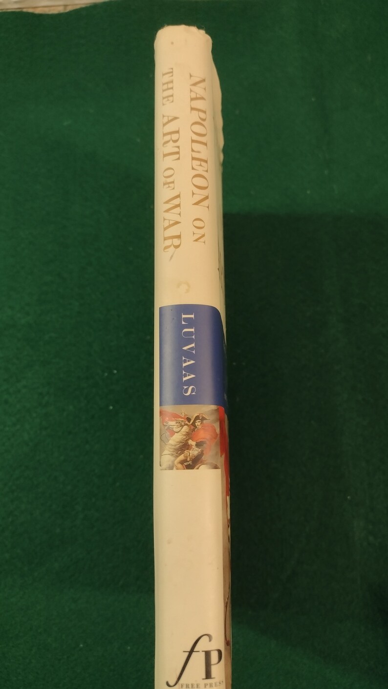 May include: A white book with gold lettering on the spine. The title is "Napoleon on the Art of War" by C. Luvaas. The book is published by the Free Press.