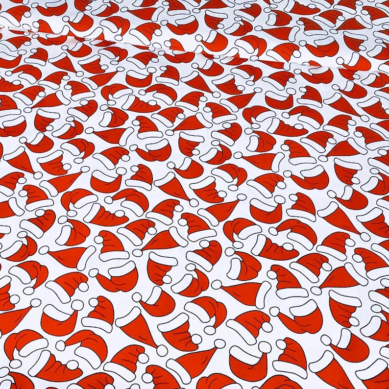 May include: White fabric with a repeating pattern of red Santa hats. The hats are outlined in black and have a white pom-pom on top.