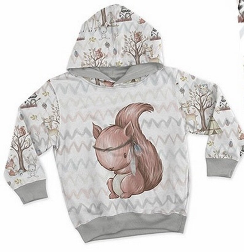 May include: A gray hooded sweatshirt with a white and brown woodland animal print. The print features a squirrel with a feather headband and a chevron pattern.