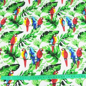 May include: White fabric with a repeating pattern of colorful parrots and green tropical leaves. The fabric is measured with a tape measure.