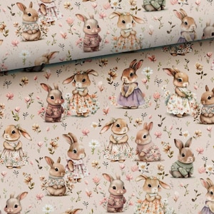 May include: A beige fabric with a repeating pattern of bunnies wearing dresses and sweaters. The bunnies are surrounded by small pink, white, and green flowers.