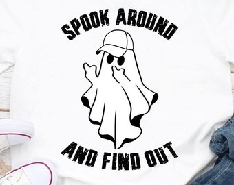 May include: White t-shirt featuring a black graphic of a ghost wearing a cap and giving the middle finger. The text "SPOOK AROUND AND FIND OUT" is printed above and below the ghost illustration.