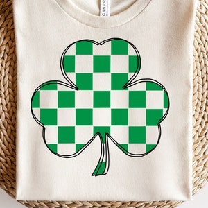 May include: A white t-shirt featuring a green and white checkered shamrock design.