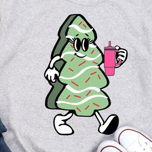 May include: A green Christmas tree with red and white sprinkles, wearing sunglasses and holding a pink cup with a straw. The tree is walking with large white shoes.