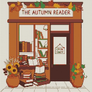 May include: A cross-stitch pattern depicting a storefront titled THE AUTUMN READER, featuring brown wood framing, a large window displaying stacks of books, and two terracotta pots filled with sunflowers and autumn foliage on either side.