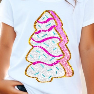 May include: A white t-shirt featuring a sparkly gold, pink and blue Christmas tree design. The tree is decorated with sprinkles and a pink ribbon.
