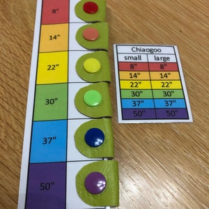 May include: A color-coded chart with different sizes of knitting needles, labeled in inches. The chart includes a table with the sizes of small and large knitting needles.