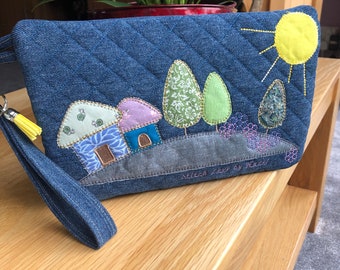 Denim quilted zip bag with appliqué design and detachable wrist strap/key fob.