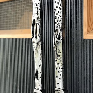 May include: Two silver door handles with unique textured designs. The handles are mounted on a black ribbed surface.