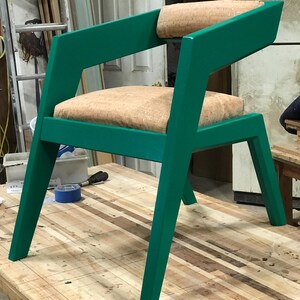 May include: A green chair with a cork-covered seat and back. The chair has a unique, angular design with a wide, flat back and angled legs.