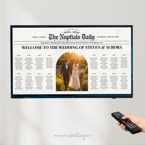 Puede incluir: Una pantalla digital muestra un plano de asientos de boda diseñado como una portada de periódico. El titular dice "The Nuptials Daily" con la fecha del 20 de junio de 2026. Los nombres de los invitados se enumeran debajo de los números de mesa. Un mando a distancia se sostiene en la mano.