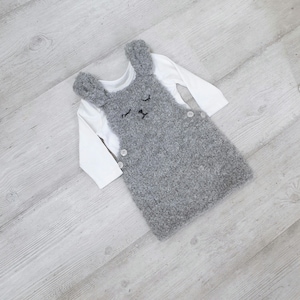 May include: Grey fuzzy bunny-shaped baby overall with white long-sleeved shirt underneath.