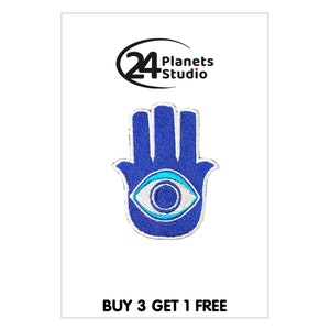 May include: Blue embroidered patch featuring a hamsa hand design with a blue evil eye in the centre. The patch has white stitching around the edges. The text "BUY 3 GET 1 FREE" is at the bottom of the image.