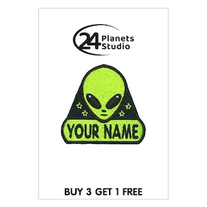 Puede incluir: Cara de extraterrestre verde con ojos negros y contorno negro. El extraterrestre lleva un sombrero negro con estrellas blancas. El extraterrestre está en una pancarta negra con el texto "YOUR NAME" en blanco.