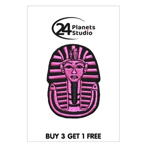 May include: Pink embroidered iron-on patch of an Egyptian pharaoh's head with a black outline. The patch features the text "24 Planets Studio" and "BUY 3 GET 1 FREE".