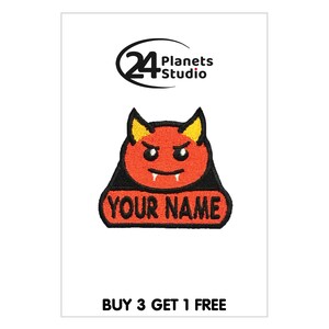 May include: Red and yellow embroidered iron-on patch of a cartoon devil with the text "YOUR NAME" below.