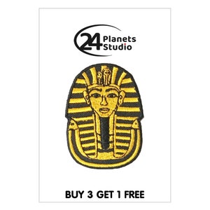 Könnte beinhalten: Ein gestickter Bügelaufkleber mit einem goldenen Pharaonenkopf auf schwarzem Hintergrund. Der Aufnäher trägt den Text "BUY 3 GET 1 FREE" unten.