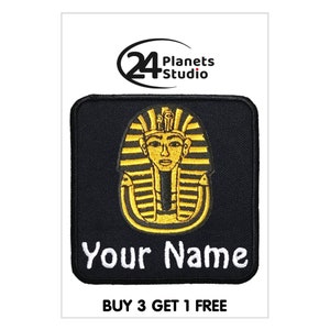 Könnte beinhalten: Schwarzer gestickter Bügel-Patch mit einem goldenen Pharaonenkopf-Design und dem Text "Your Name".