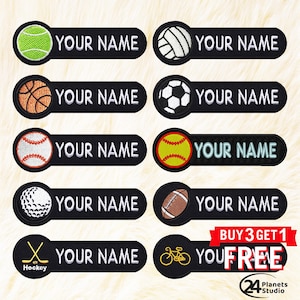 Peut inclure: Ensemble de dix patchs thermocollants représentant divers symboles sportifs, dont un ballon de basket, un ballon de baseball, un ballon de football, un ballon de volley-ball, une balle de golf, un ballon de football américain, un bâton de hockey et un vélo. Chaque patch a un fond noir avec du texte blanc qui dit "YOUR NAME".