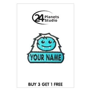 Puede incluir: Un parche bordado azul y blanco para planchar con un yeti de dibujos animados con una cara sonriente y el texto "YOUR NAME".