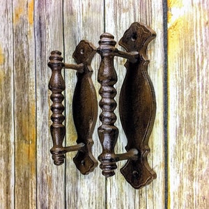 May include: Three antique-style cast iron door pulls with a dark brown finish. The pulls have a decorative, ornate design with a fluted handle.