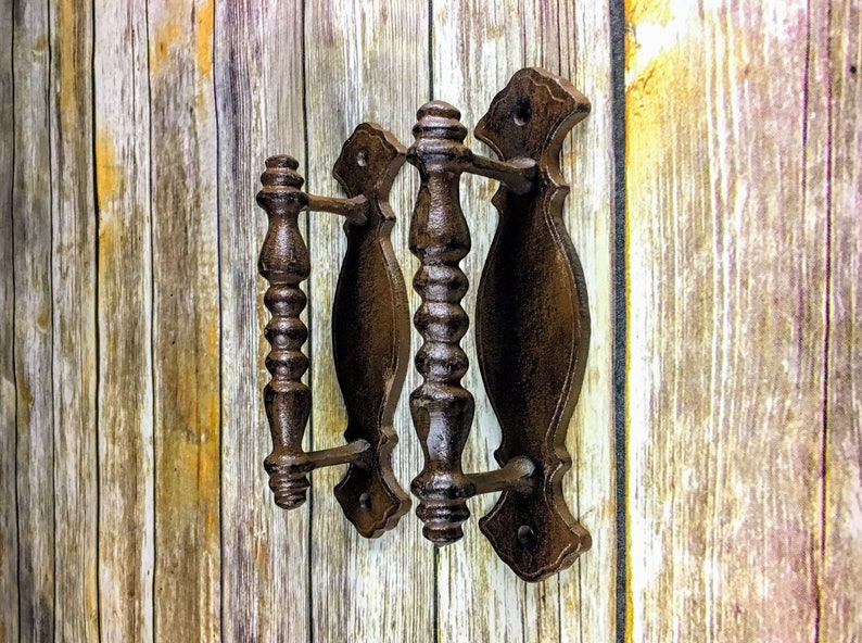 May include: Three antique-style cast iron door pulls with a dark brown finish. The pulls have a decorative, ornate design with a fluted handle.
