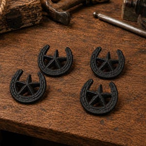 Puede incluir: Cuatro adornos de hierro fundido negro, cada uno con forma de herradura y una estrella de cinco puntas centrada en el arco. Las piezas presentan un acabado mate y texturizado, dispuestas en formación cuadrada sobre madera.