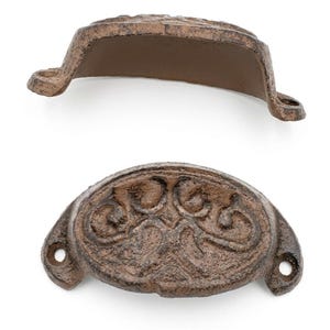 Peut inclure: Deux poign&eacute;es de tiroir en fonte de style antique, marron. L'une est vue de c&ocirc;t&eacute;, l'autre de face. La poign&eacute;e orient&eacute;e vers l'avant pr&eacute;sente un motif floral orn&eacute;. Chaque poign&eacute;e a deux trous de montage.