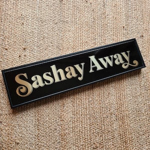 May include: Black sign with gold lettering that reads "Sashay Away".