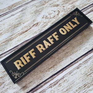 Pu&ograve; includere: Un cartello in legno nero con lettere dorate che recita "Riff Raff Only".