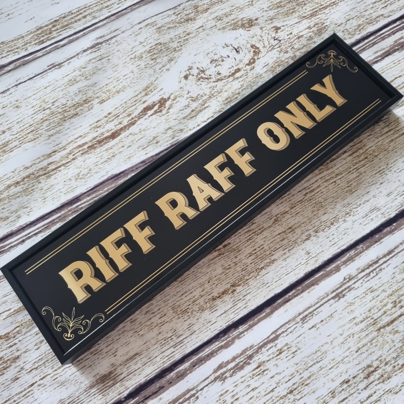 Pu&ograve; includere: Un cartello in legno nero con lettere dorate che recita "Riff Raff Only".
